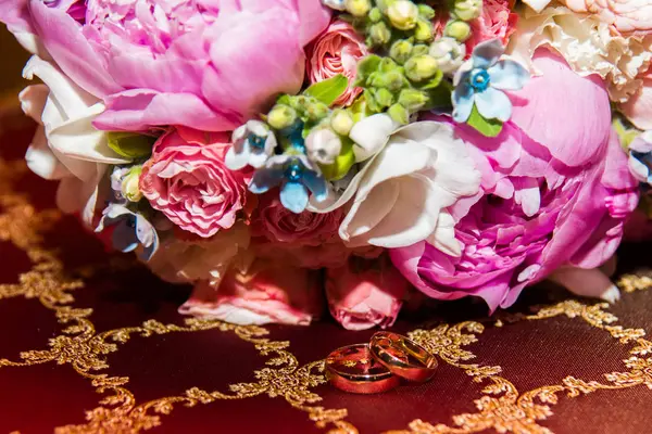 新娘和新郎的结婚戒指在粉红色牡丹和玫瑰的美丽婚礼花束 — 图库照片