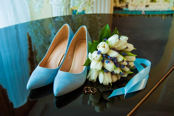 Wedding rings of the bride and groom on a Beautiful wedding bouquet of white tulips. Blue wedding shoes — Stock Photo, Image