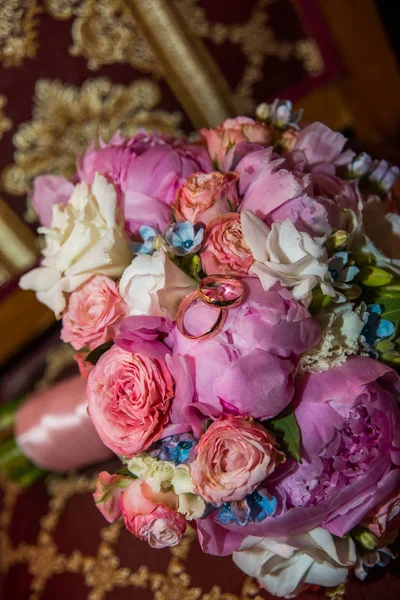 Trauringe des Brautpaares an einem wunderschönen Brautstrauß aus rosa Pfingstrosen und Rosen — Stockfoto