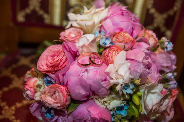 Trouwringen van de bruid en bruidegom op een mooie bruiloft boeket van roze pioenrozen en rozen — Stockfoto