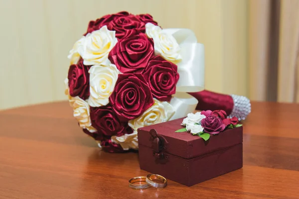 Anéis de casamento da noiva e do noivo em um lindo buquê de casamento de rosas vermelhas e brancas. Caixa de madeira para anéis de casamento — Fotografia de Stock