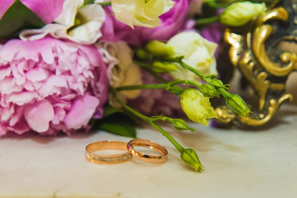 Belo buquê de casamento delicado de peônias rosa e anéis de casamento da noiva e do noivo . — Fotografia de Stock