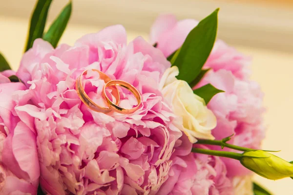 Hermoso ramo de boda delicado de peonías rosadas y anillos de boda de la novia y el novio . — Foto de Stock