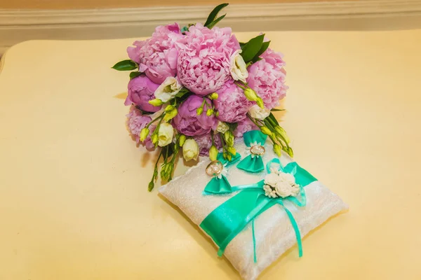 Mooie delicate bruiloft boeket van roze pioenrozen en trouwringen van de bruid en bruidegom. — Stockfoto