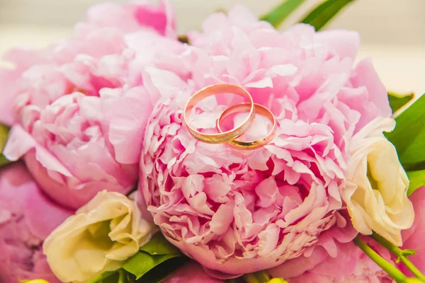 Mooie delicate bruiloft boeket van roze pioenrozen en trouwringen van de bruid en bruidegom. — Stockfoto