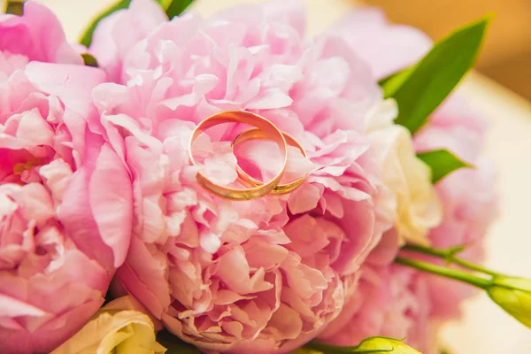 Bellissimo bouquet da sposa delicato di peonie rosa e fedi nuziali degli sposi . — Foto Stock