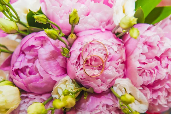 Hermoso ramo de boda delicado de peonías rosadas y anillos de boda de la novia y el novio . —  Fotos de Stock