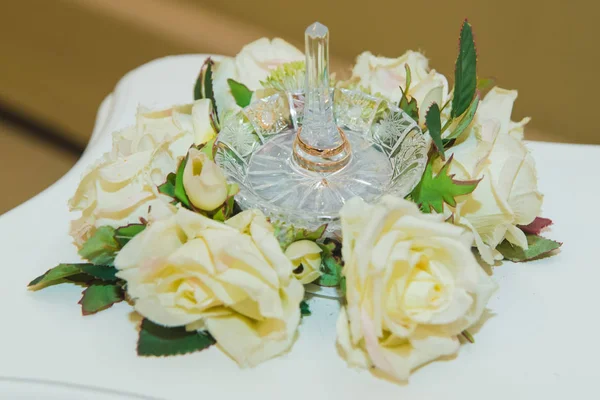 Anillos de boda en un soporte de cristal de rosas blancas . — Foto de Stock