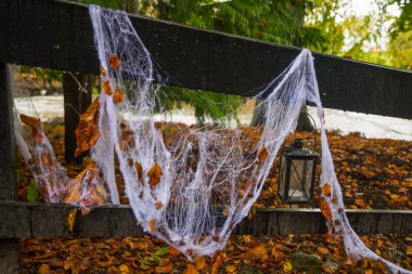 Sonbahar ormanlarında Cadılar Bayramı 'nda tahta köprüde beyaz örümcek ağı ve fener..