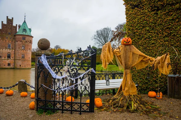 Egeskov Slot, Denmark, Halloween: Scarecrows and pumpkins decorate the entrance to the bridge to the Egeskov Castle in autumn.