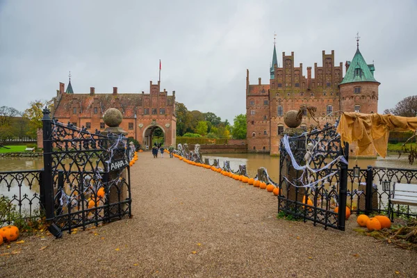 Egeskov Slot , Denmark, Halloween: Scarecrows and pumpkins decorate the entrance to the bridge to the Egeskov Castle in autumn.