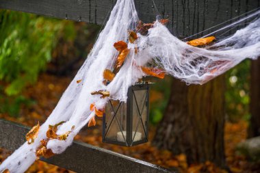 Sonbahar ormanlarında Cadılar Bayramı 'nda tahta köprüde beyaz örümcek ağı ve fener..