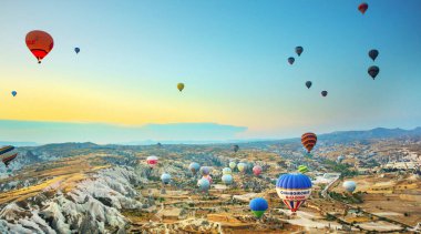 Kapadokya, Türkiye: Kapadokya Bölgesi 'nde sıcak hava balonları gün doğumunda uçuyor. Mavi gökyüzüne karşı uçan balon, renkli eğlenceli ulaşım biçimi, balonun havasında uçmak, rüya ve mutluluk kavramı.