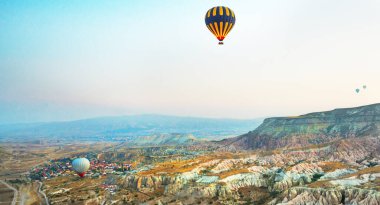 Kapadokya, Türkiye: Kapadokya Bölgesi 'nde sıcak hava balonları gün doğumunda uçuyor. Mavi gökyüzüne karşı uçan balon, renkli eğlenceli ulaşım biçimi, balonun havasında uçmak, rüya ve mutluluk kavramı.