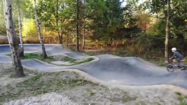 Niño montando una bicicleta en una pista de calabaza — Vídeos de Stock