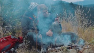 Genç çift oturma yakınındaki dağlarda kamp ateşi sevgi dolu