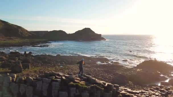 女性北アイルランドのジャイアンツ コーズウェー岩の景色を楽しみながらの空中ショット — ストック動画