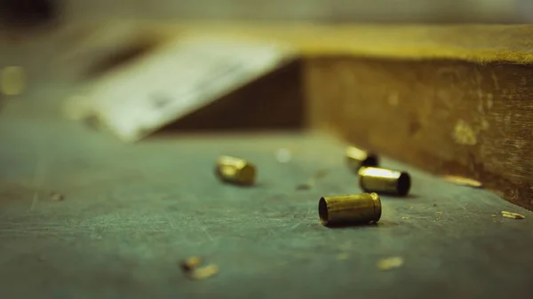 Cartuchos de bala de pistola vacíos en una mesa de madera en un campo de tiro — Foto de Stock