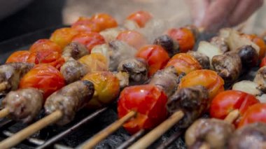 Sıcak barbekü ızgarasında domatesli ve soğanlı tavuk kalbi pişirmekten yayılan dumanın sineması. Kapat, seçici odaklı döngü.