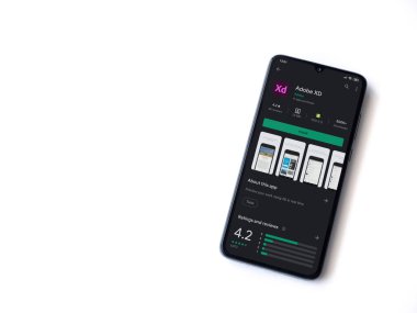 Lod, Israel - 8 Temmuz 2020: Adobe XD uygulama oyun mağazası sayfası beyaz arkaplanda izole edilmiş siyah bir cep telefonu ekranında. Üst görünüm düzlüğü kopyalama alanı ile yatıyordu. 
