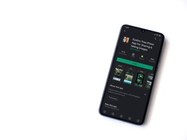 Lod, Israel - 8 Temmuz 2020: EyeEm - Resimleri Paylaşım ve Satma uygulamaları oyun mağazası sayfası beyaz arkaplanda izole edilmiş siyah bir cep telefonu ekranında. Üst görünüm düzlüğü kopyalama alanı ile yatıyordu.