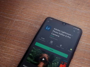Lod, Israel - 8 Temmuz 2020: Adobe Lightroom - Fotoğraf Editörü ve Pro Camera uygulaması oyun sayfası ahşap arka planda siyah bir cep telefonu sergilenmektedir. Üst görünüm düzlüğü kopyalama alanı ile yatıyordu.