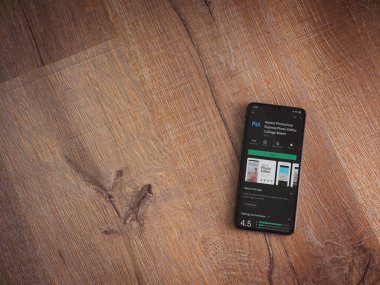 Lod, Israel - 8 Temmuz 2020: Adobe Photoshop Express Fotoğraf Editörü uygulama oyun sayfası ahşap arka planda siyah bir cep telefonunun ekranında. Üst görünüm düzlüğü kopyalama alanı ile yatıyordu.