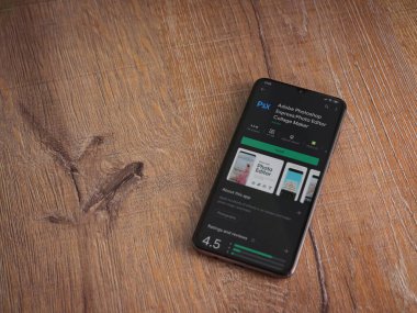 Lod, Israel - 8 Temmuz 2020: Adobe Photoshop Express Fotoğraf Editörü uygulama oyun sayfası ahşap arka planda siyah bir cep telefonunun ekranında. Üst görünüm düzlüğü kopyalama alanı ile yatıyordu.