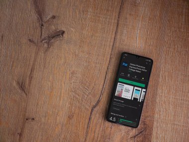 Lod, Israel - 8 Temmuz 2020: Adobe Photoshop Express Fotoğraf Editörü uygulama oyun sayfası ahşap arka planda siyah bir cep telefonunun ekranında. Üst görünüm düzlüğü kopyalama alanı ile yatıyordu.