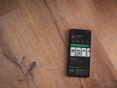 Lod, Israel - 8 Temmuz 2020: Adobe XD uygulaması oyun mağazası sayfası ahşap arka planda siyah bir cep telefonunun ekranında. Üst görünüm düzlüğü kopyalama alanı ile yatıyordu. 