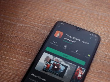 Lod, Israel - 8 Temmuz 2020: Autodesk SketchBook - Ahşap arka planda siyah bir cep telefonu sergisi üzerine uygulama oyun mağazası sayfası çiz ve boya. Üst görünüm düzlüğü kopyalama alanı ile yatıyordu.
