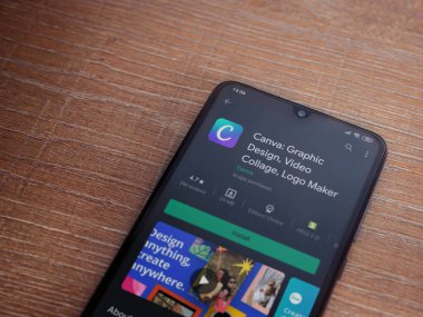 Lod, Israel - 8 Temmuz 2020: Canva - Grafik Tasarım uygulaması oyun mağazası sayfası, ahşap arka planda siyah bir cep telefonu görüntüsü. Üst görünüm düzlüğü kopyalama alanı ile yatıyordu. 