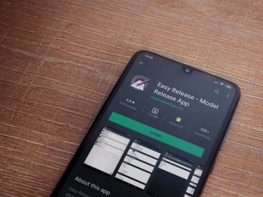 Lod, Israel - 8 Temmuz 2020: Easy Release Pro - Model Sürüm uygulaması oyun mağazası sayfası ahşap arka planda siyah bir cep telefonu görüntüsü. Üst görünüm düzlüğü kopyalama alanı ile yatıyordu. 