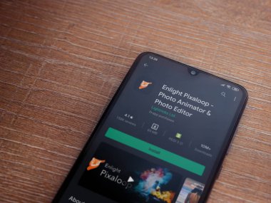 Lod, Israel - 8 Temmuz 2020: Pixaloop uygulaması oyun mağazası sayfasını ahşap arka planda siyah bir cep telefonunun ekranında aydınlat. Üst görünüm düzlüğü kopyalama alanı ile yatıyordu.