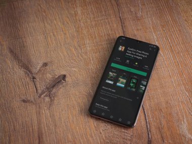 Lod, Israel - 8 Temmuz 2020: EyeEm - Ahşap arka planda siyah bir cep telefonunun ekranında resim paylaşımı ve satışı uygulaması oyun sayfası. Üst görünüm düzlüğü kopyalama alanı ile yatıyordu.