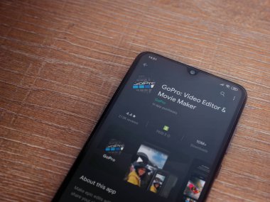 Lod, Israel - 8 Temmuz 2020: GoPro - Video Editörü ve Film Yapımcısı uygulama oyun sayfası ahşap arka planda siyah bir cep telefonunun ekranında. Üst görünüm düzlüğü kopyalama alanı ile yatıyordu.