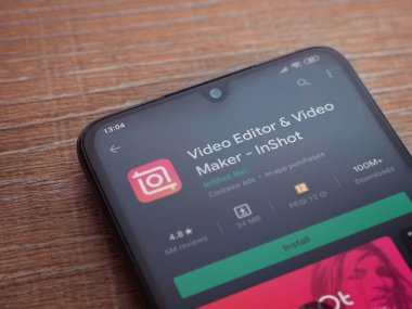 Lod, Israel - 8 Temmuz 2020: Inshot - Video Editörü ve Film Yapımcısı uygulama oyun sayfası ahşap arka planda siyah bir cep telefonunun ekranında. Üst görünüm düzlüğü kopyalama alanı ile yatıyordu.