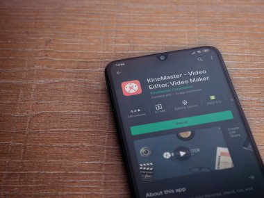 Lod, Israel - 8 Temmuz 2020: KineMaster - Video Editörü ve Film Yapımcısı uygulama oyun sayfası ahşap arka planda siyah bir cep telefonunun ekranında. Üst görünüm düzlüğü kopyalama alanı ile yatıyordu.