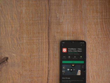 Lod, Israel - 8 Temmuz 2020: KineMaster - Video Editörü ve Film Yapımcısı uygulama oyun sayfası ahşap arka planda siyah bir cep telefonunun ekranında. Üst görünüm düzlüğü kopyalama alanı ile yatıyordu.
