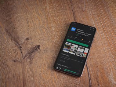 Lod, Israel - 8 Temmuz 2020: Adobe Behance uygulaması oyun mağazası sayfası ahşap arka planda siyah bir cep telefonu ekranında. Üst görünüm düzlüğü kopyalama alanı ile yatıyordu. 