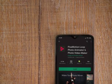 Lod, Israel - 8 Temmuz 2020: PixaMotion uygulaması oyun mağazası sayfası ahşap arka planda siyah bir cep telefonu ekranında. Üst görünüm düzlüğü kopyalama alanı ile yatıyordu.