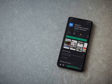 Lod, Israel - 8 Temmuz 2020: Adobe Behance uygulaması oyun mağazası sayfası seramik taş zemin üzerinde siyah bir cep telefonu görüntüsü. Üst görünüm düzlüğü kopyalama alanı ile yatıyordu. 