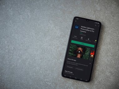Lod, Israel - 8 Temmuz 2020: Adobe Lightroom - Fotoğraf Editörü ve Pro Camera uygulama oyun sayfası seramik taş zemin üzerinde siyah bir cep telefonu sergilenmektedir. Üst görünüm düzlüğü kopyalama alanı ile yatıyordu.