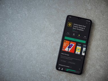 Lod, Israel - 8 Temmuz 2020: Adobe Spark Post - Grafik Tasarım ve Hikaye Şablonları uygulama oyun sayfası seramik taş arka planda siyah bir cep telefonu görüntüsü. Üst görünüm düzlüğü düz bir şekilde fotokopi alanı ile yatıyordu