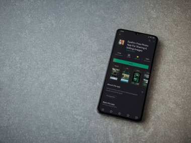 Lod, Israel - 8 Temmuz 2020: EyeEm - Seramik taş zemin üzerinde siyah bir mobil akıllı telefonun sergilendiği resimlerin paylaşımı ve satışı oyun mağazası sayfası. Üst görünüm düzlüğü kopyalama alanı ile yatıyordu.