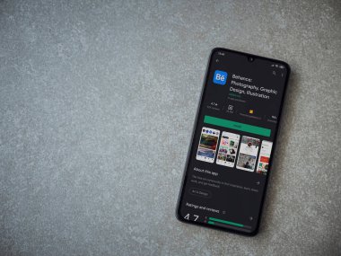 Lod, Israel - 8 Temmuz 2020: Adobe Behance uygulaması oyun mağazası sayfası seramik taş zemin üzerinde siyah bir cep telefonu görüntüsü. Üst görünüm düzlüğü kopyalama alanı ile yatıyordu. 