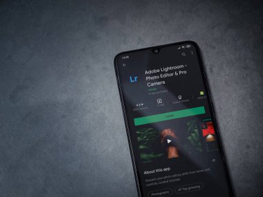 Lod, Israel - 8 Temmuz 2020: Adobe Lightroom - Fotoğraf Editörü ve Pro Camera uygulama oyun sayfası koyu renkli mermer taştan bir arka planda siyah bir cep telefonu sergilenmektedir. Üst görünüm düzlüğü kopyalama alanı ile yatıyordu.