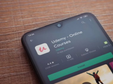 Lod, Israel - 8 Temmuz 2020: Ahşap arka planda siyah bir cep telefonunun ekranında Udemy uygulaması oyun mağazası sayfası. Üst görünüm düzlüğü kopyalama alanı ile yatıyordu.