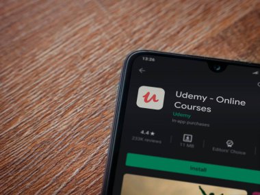 Lod, Israel - 8 Temmuz 2020: Ahşap arka planda siyah bir cep telefonunun ekranında Udemy uygulaması oyun mağazası sayfası. Üst görünüm düzlüğü kopyalama alanı ile yatıyordu.