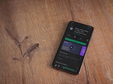 Lod, Israel - 8 Temmuz 2020: Mimo - Ahşap arka planda siyah bir cep telefonunun ekranında kodlama uygulaması oyun mağazası sayfası öğreniyor. Üst görünüm düzlüğü kopyalama alanı ile yatıyordu.